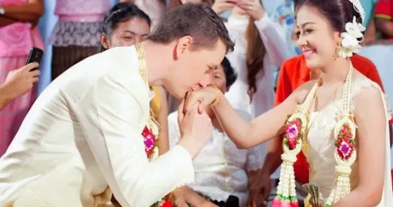 Свадебная церемония в Пхукете: жених целует руку невесты среди гостей.