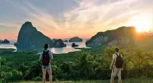 Couple gazing at a stunning sunset over lush islands in Phuket, Thailand.