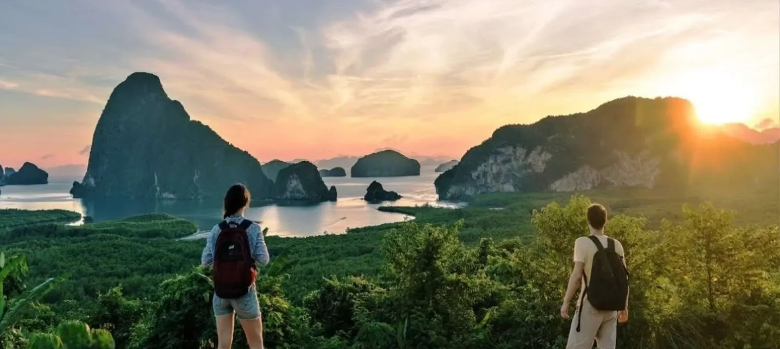 Couple gazing at a stunning sunset over lush islands in Phuket, Thailand.
