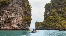 Kayakers exploring turquoise waters between towering limestone cliffs in Phuket.