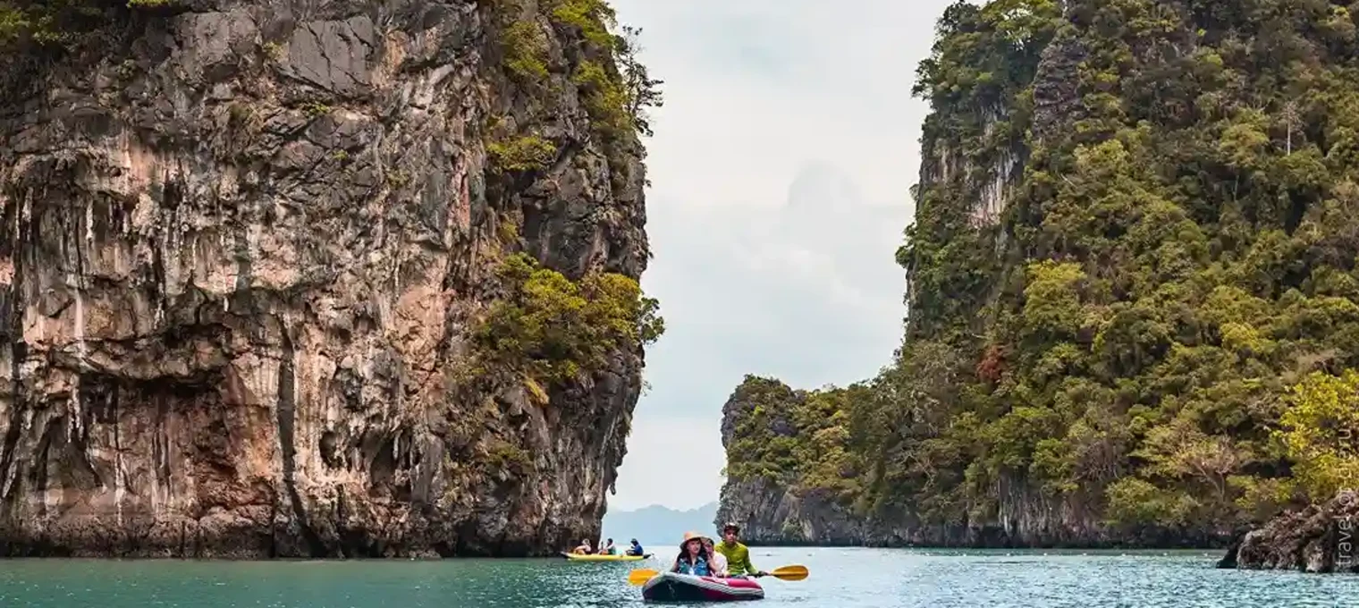 Kayakers exploring turquoise waters between towering limestone cliffs in Phuket.