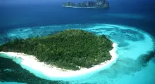 Aerial view of a tropical island surrounded by clear blue waters in Phuket, Thailand.