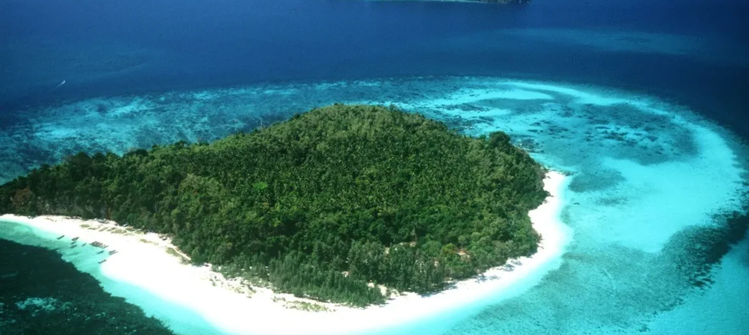 Aerial view of a tropical island surrounded by clear blue waters in Phuket, Thailand.