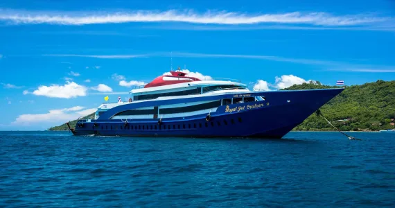 Luxury cruise ship docked near the scenic coast of Phuket under a bright blue sky.