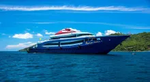 Luxury cruise ship docked near the scenic coast of Phuket under a bright blue sky.