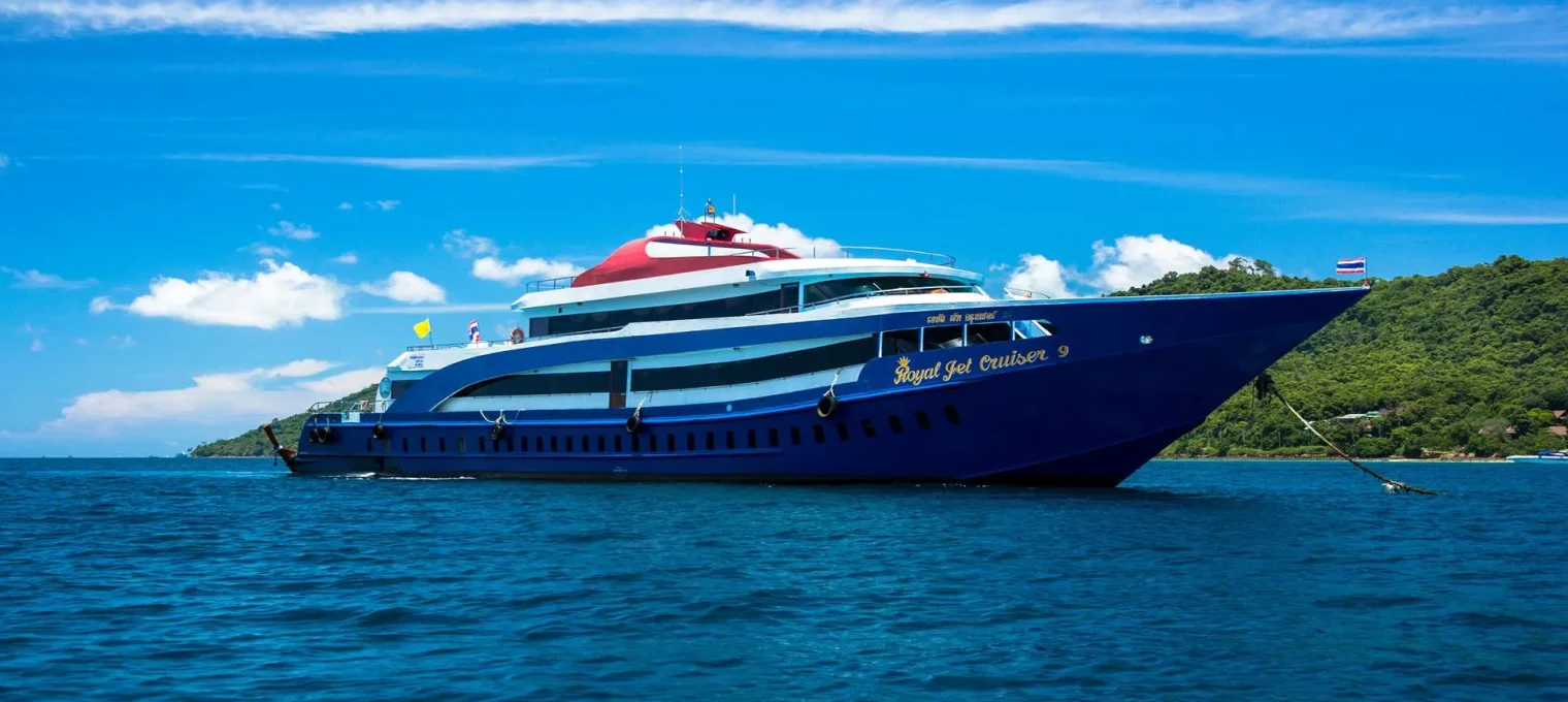 Luxury cruise ship docked near the scenic coast of Phuket under a bright blue sky.
