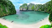 Stunning beach with turquoise water, limestone cliffs, and boats in Phuket, Thailand.
