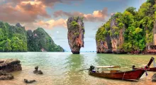 Phuket landscape featuring limestone cliffs, clear waters, and a traditional boat.