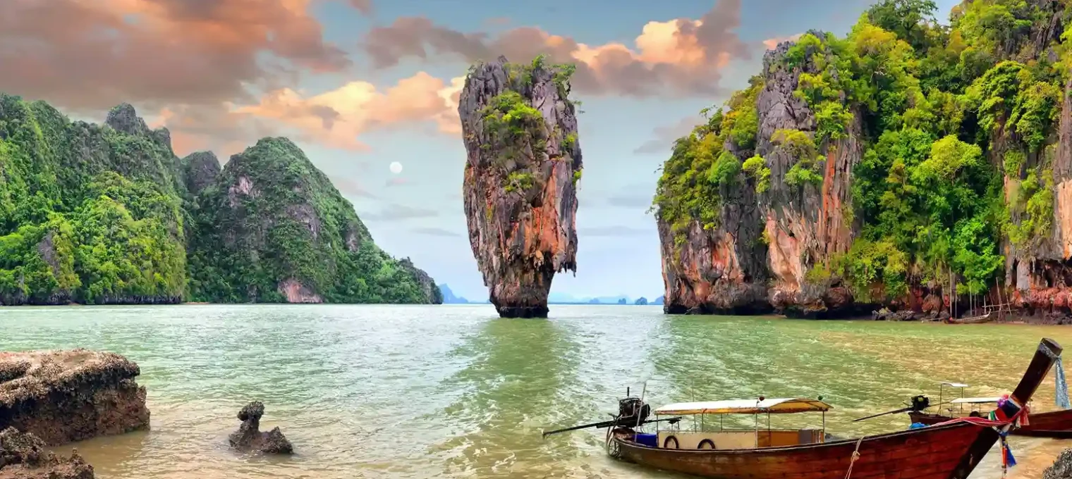 Phuket landscape featuring limestone cliffs, clear waters, and a traditional boat.