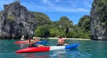 Colorful kayaks on a clear water lake, with people paddling near lush cliffs in Phuket.