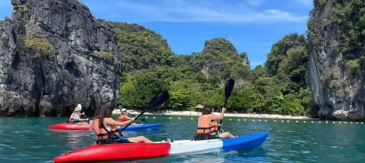 Colorful kayaks on a clear water lake, with people paddling near lush cliffs in Phuket.