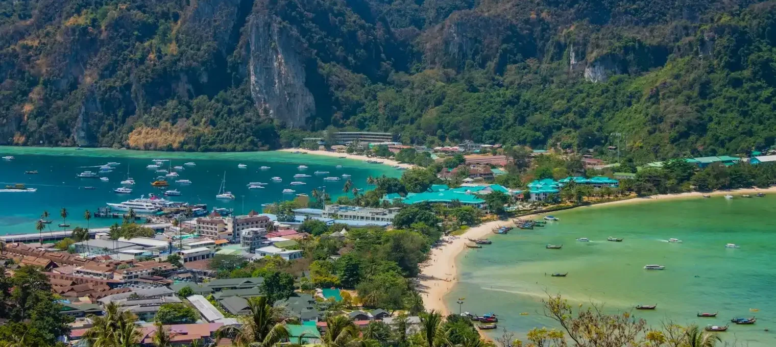 Scenic view of Phuket’s coastline with boats, greenery, and mountains in the background.