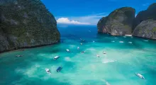 Aerial view of turquoise waters and boats near rocky cliffs in Phuket, Thailand.