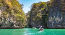 Scenic view of turquoise waters and limestone cliffs in Phuket, Thailand, with boats.