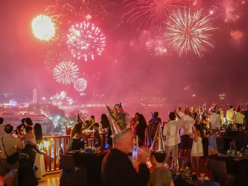 Фейерверк над Пхукетом на фоне вечеринки с людьми и столами. Сияние огней.