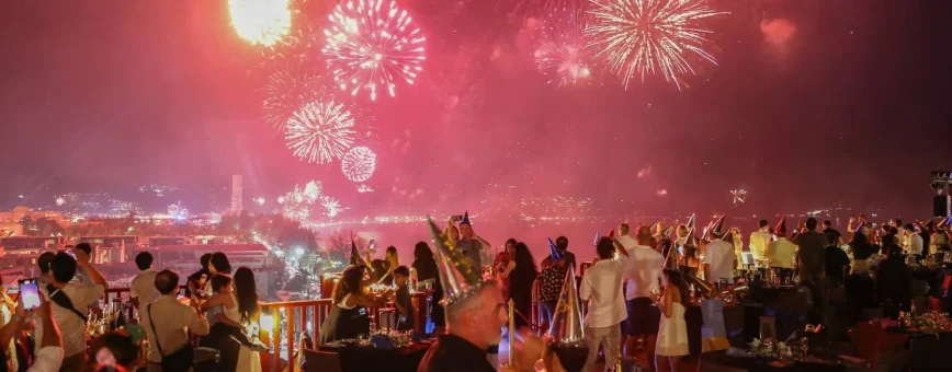 Фейерверк над Пхукетом на фоне вечеринки с людьми и столами. Сияние огней.