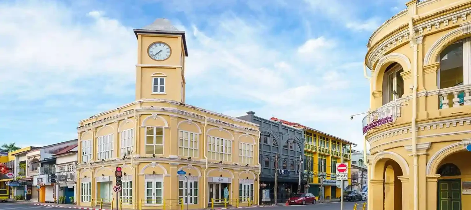 Colorful historic buildings with a clock tower in Phuket, Thailand under a bright sky.