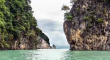 Lush limestone cliffs framing calm turquoise waters in Phuket, Thailand.