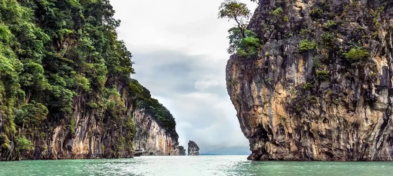Lush limestone cliffs framing calm turquoise waters in Phuket, Thailand.