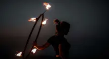 A person performing with flaming hula hoops against a dark sky in Phuket.