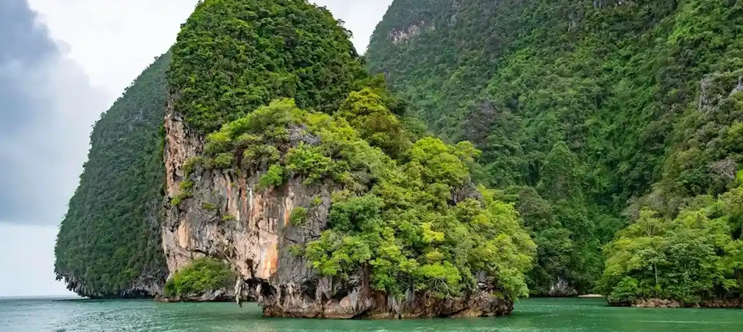 Lush green island surrounded by turquoise waters in Phuket, Thailand.