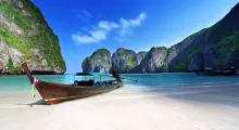 Beautiful beach in Phuket with a traditional boat and stunning limestone cliffs.