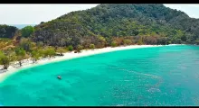 Stunning turquoise waters and white sandy beach in Phuket, surrounded by lush greenery.