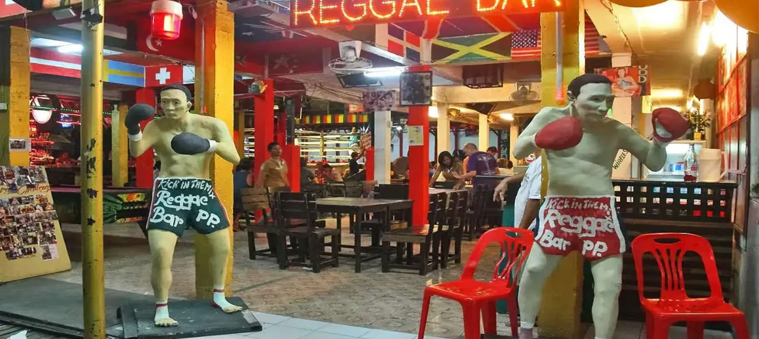 Two boxing statues outside a reggae bar in Phuket, vibrant with colorful decor.