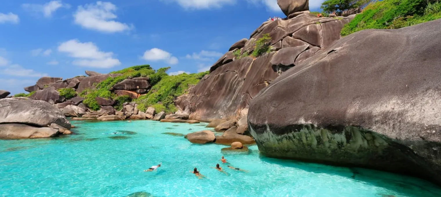 Кристально чистая вода и скальные образования на пляже в Пхукете. Люди отдыхают.